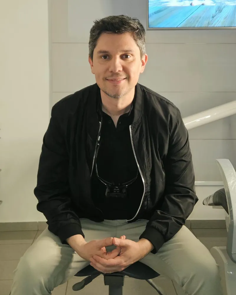 Dr. Fabio Vanzelli sentado no consultório da clínica, com lupa de aumento